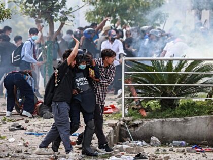 Demonstrators carry an injured police personnel during a protest outside the Parliament in