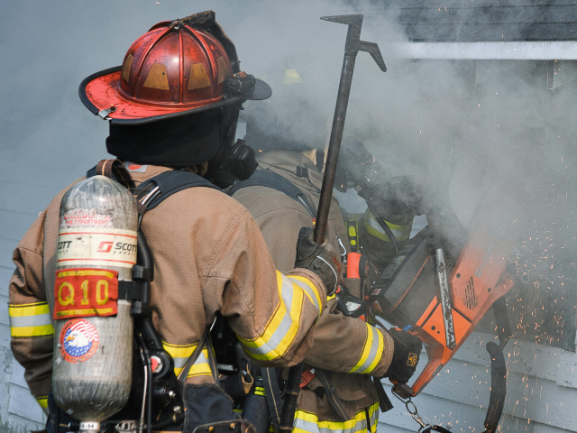 Firefighters Cutting Hole in Burning House