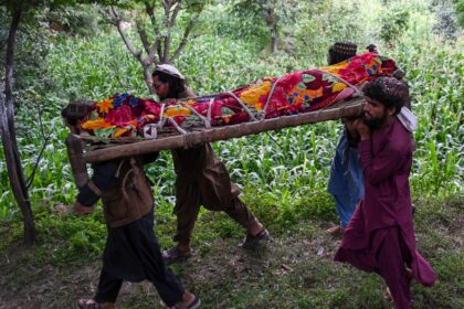 Afghan men carry the shrouded body of an earthquake victim for burial in Nurgal, Junar pro