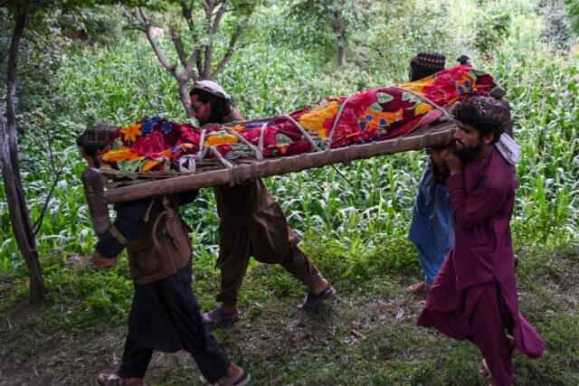 Afghan men carry the shrouded body of an earthquake victim for burial in Nurgal, Junar pro