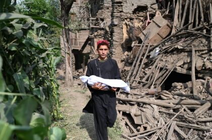 An Afghan boy carries the body of a relative following earthquakes eastern Afghanistan