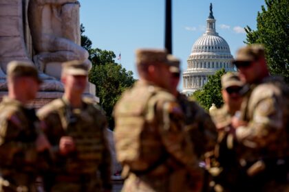 The US Capitol building is visible as armed members of the National Guard stand outside Un