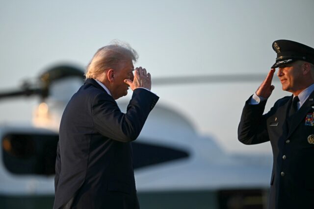 US President Donald Trump salutes as he boards Air Force One at Joint Base Andrews in Mary