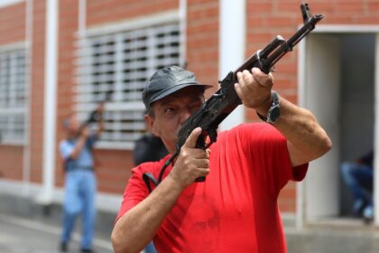 A Venezuela militia member receives weapon training from the military in the midst of a sh