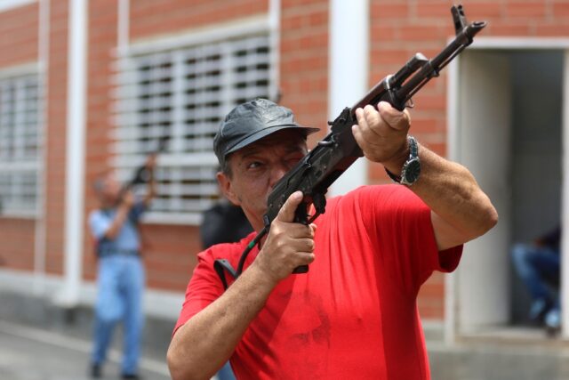 A Venezuela militia member receives weapon training from the military in the midst of a sh