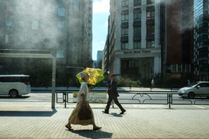 A woman with an umbrella walks in the scorching sun in Tokyo on September 1