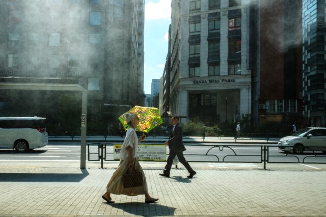 A woman with an umbrella walks in the scorching sun in Tokyo on September 1