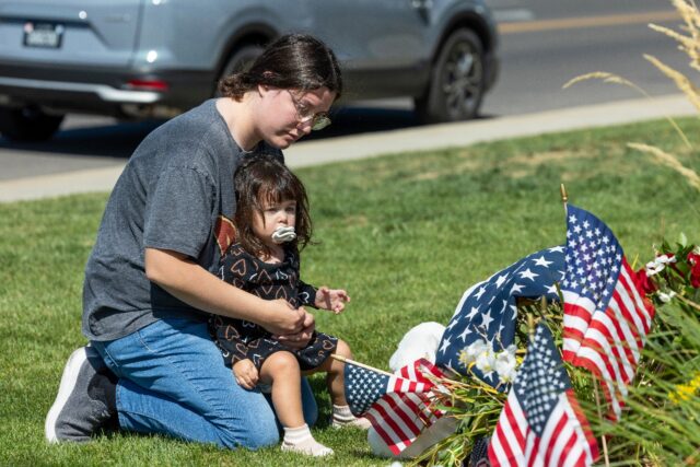 A woman pays tribute to Charlie Kirk at a memorial set up outside of Timpanogos Regional H