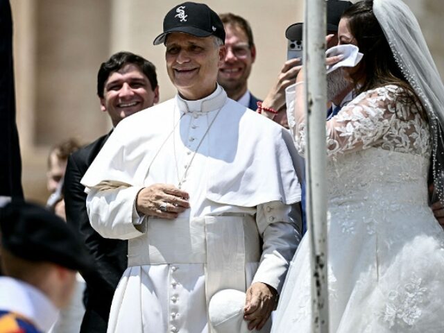 FILIPPO MONTEFORTE_AFP via Getty Images (1) Pope Leo XIV (C) reacts wearing a Chicago White Sox baseball team cap as he meets newly we