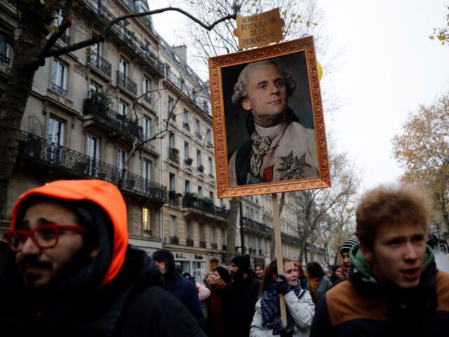 TOPSHOT - A woman holds a portrait of French President Emmanuel Macron painted as a royalt