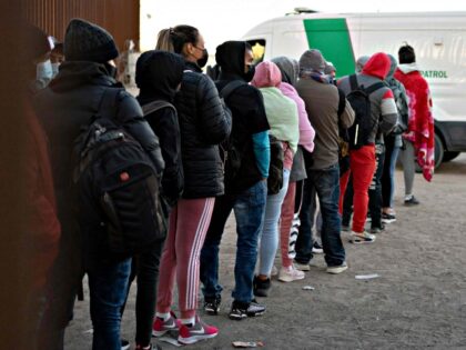Asylum-seekers line up to be processed by US Customs and Border Patrol agents at a gap in