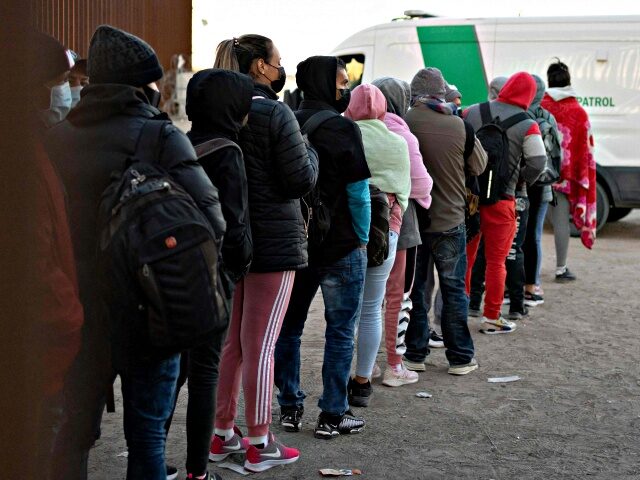 US-IMMIGRATION-BORDER-LAW ENFORCEMENT-TITLE 42 Asylum-seekers line up to be processed by US Customs and Border Patrol agents at a gap in