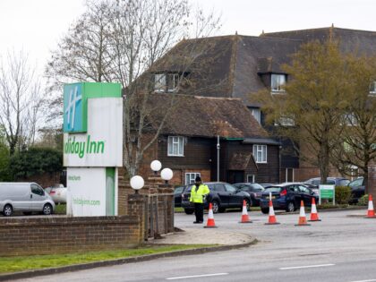 A security guard stands at the entrance to The Holiday Inn, a hotel housing migrants seeki