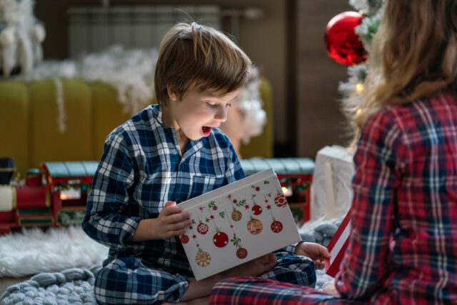 Surprised little boy opening Christmas present Surprised little boy opening Christmas present whit her sister at home