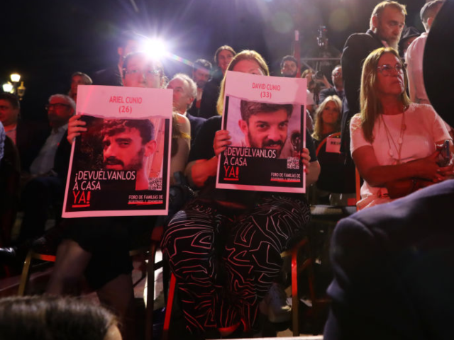 GettyImages-1843522984 BUENOS AIRES, ARGENTINA - DECEMBER 12: Attendants hold up portraits of Hamas' hostages Ari