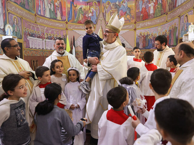 PALESTINIAN-RELIGION-CHRISTIANITY-CHRISTMAS-ISRAEL-CONFLICT Latin Patriarch of Jerusalem Pierbattista Pizzaballa (C) poses for a picture with people a