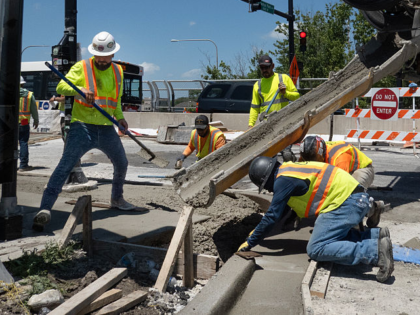 CHICAGO, ILLINOIS - JUNE 23: Construction workers finish concrete as temperatures climbed