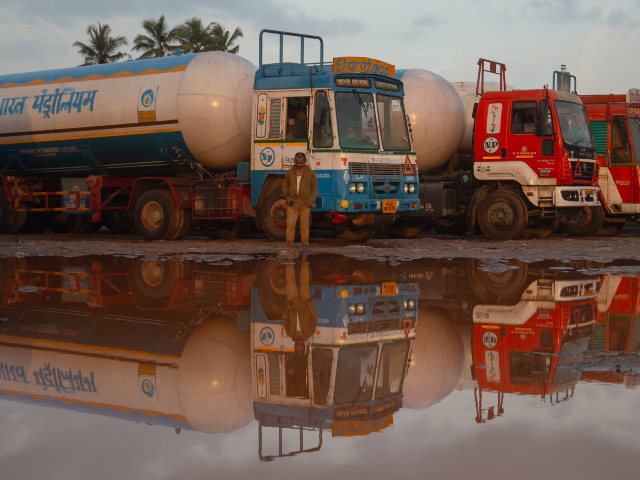 GettyImages-2233856307 MANGALURU, INDIA - SEPTEMBER 05: A truck driver and parked trucks are reflected in a puddl