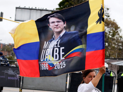 A person waves a Colombian flag with a picture of Miguel Uribe Turbay during the funeral a