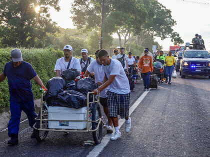Migrants are escorted by Mexican army patrols while walking along the highway as part of a