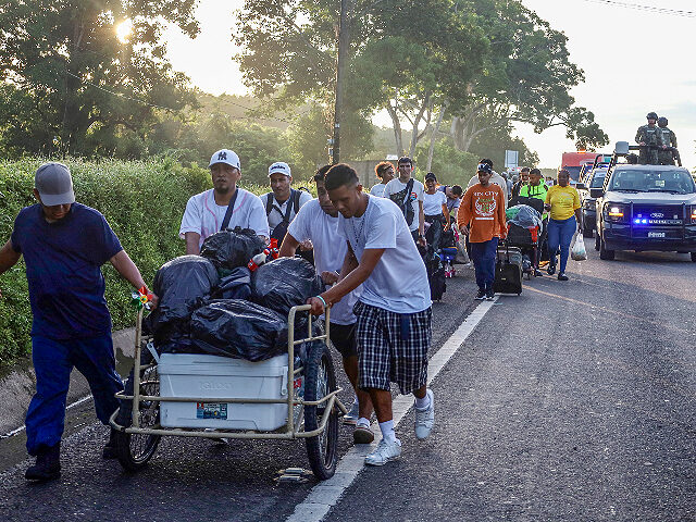Migrants are escorted by Mexican army patrols while walking along the highway as part of a