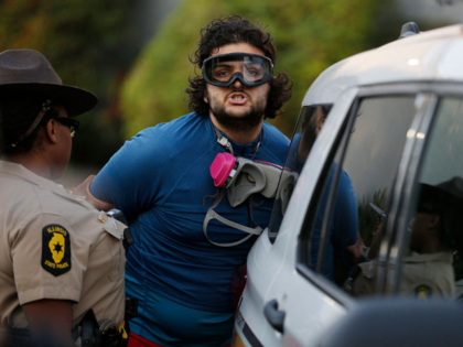 Local and state law enforcement detain a man as hundreds of protesters gather near an Immi