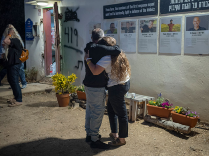 07 October 2025, Israel, Kfar Aza: Two people embrace during a ceremony commemorating the