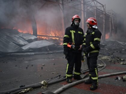 Ukrainian firefighters work at the site of a food warehouse following a Russian missile st