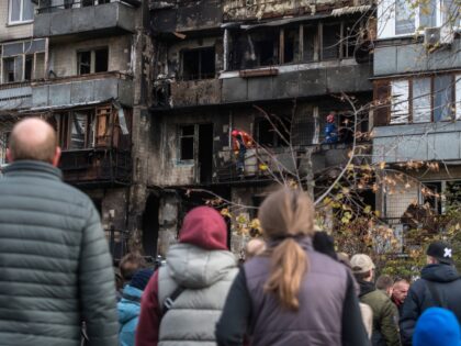 People stand in front of a residential building hit during an overnight Russian drone stri