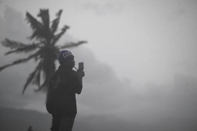TOPSHOT-JAMAICA-WEATHER-STORM-MELISSA TOPSHOT - A man uses his cellphone at the waterfront in Kingston on October 27, 2025. Hurr