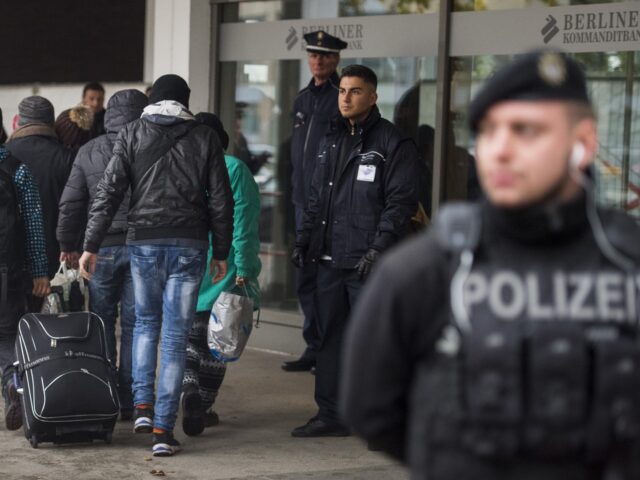 Police guards stand as asylum seekers arrive at a new registration center of the Office of