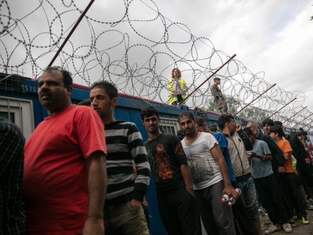 HORGOS, SERBIA - JULY 16: Migrants queue for food being distributed from a doorway in the
