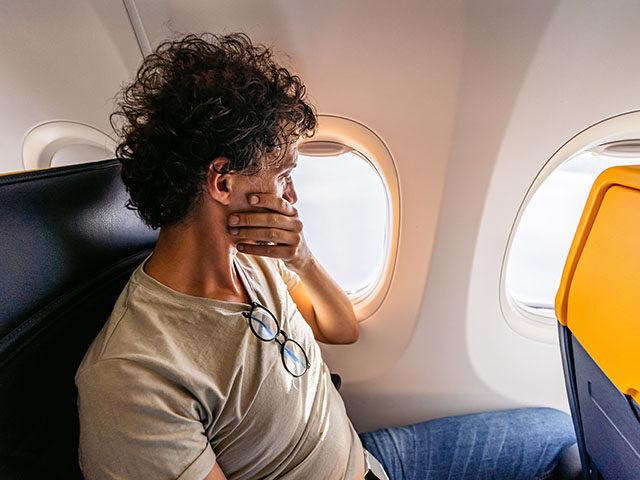 GettyImages1439973432 Scared Male Passenger Looking Out The Window Of An Airplane - stock photo