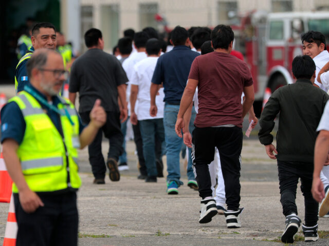 People deported from the United States walk into a processing center after arriving on a r