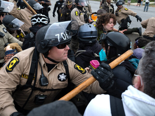 Police clash with demonstrators protesting near the immigration processing and detention f