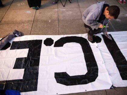 A protester paints a sign outside of the U.S. Immigration and Customs Enforcement facility