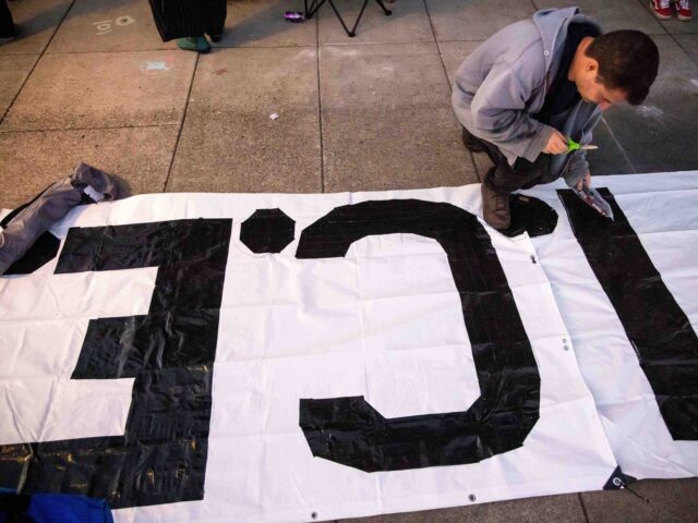 ICE protest Portland (Ethan Swope / Associated Press) A protester paints a sign outside of the U.S. Immigration and Customs Enforcement facility