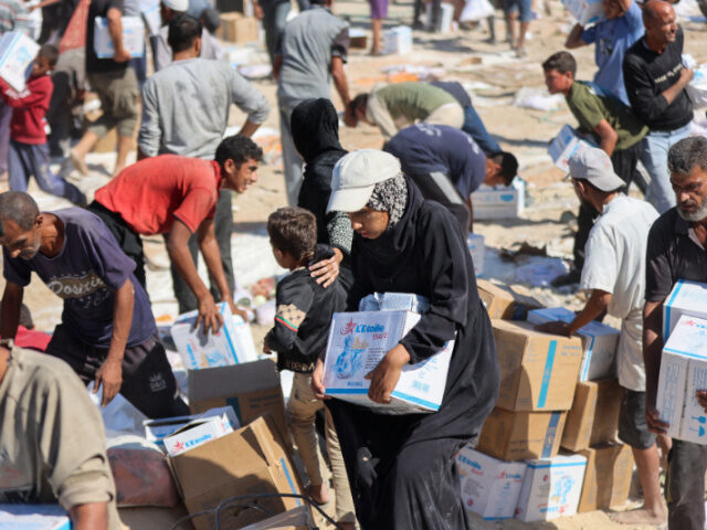 Palestinians receive food parcels after aid trucks entered from the Karem Abu Salem crossi