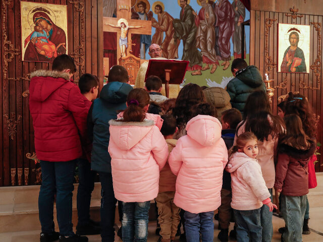 Children pray with Father Jalal Ghazal during Sunday Mass at the Church of Saint George in