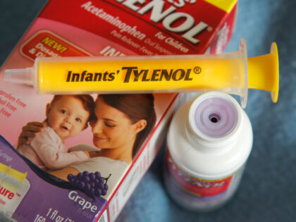 A container of grape-flavored Infants' Tylenol liquid medicine with the enclosed syri