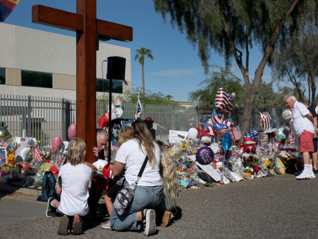 Wood Cross TPUSA Dan Beazley prays with people, as he holds a cross, at the makeshift memorial for Charlie