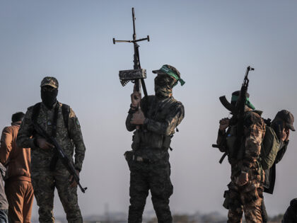Armed Hamas militants watch as thousands of Palestinians walk towards their homes in north