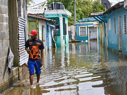 A couple leaves their flooded house after the passing of the tropical storm Melissa before