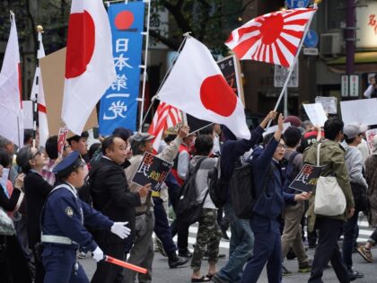 Demonstrators hold flags and placards as they march during a rally against Japan Prime Min