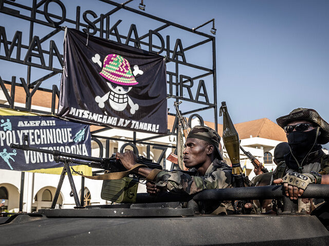 TOPSHOT - Members of Madagascar's Army CAPSAT unit ride an armoured vehicle past a large b