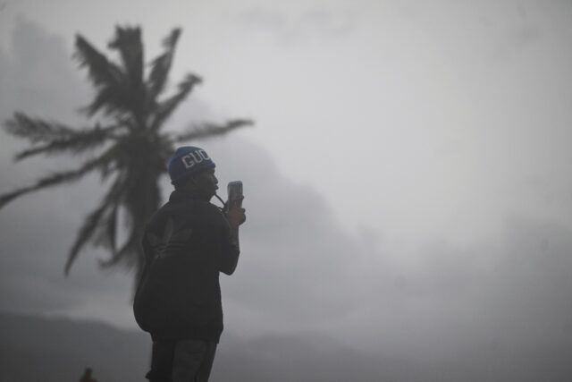 A man uses his cellphone at the waterfront in Kingston on October 27, 2025 as Hurricane Me