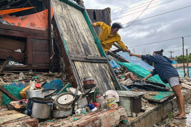 A family salvages belongings from the rubble of their home after it collapsed during Hurri