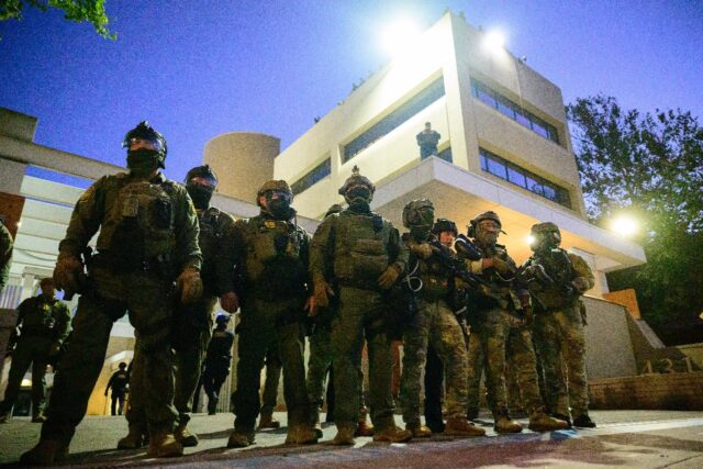 Federal agents stand guard outside an Immigration and Customs Enforcement facility in Port