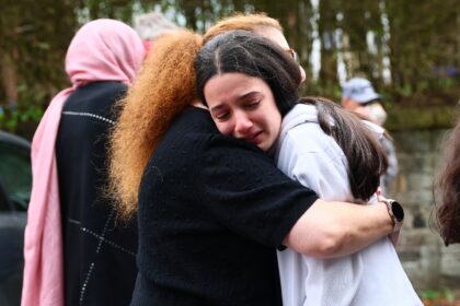 Members of the community comfort each other near Heaton Park Hebrew Congregation Synagogue