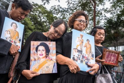 People hold portraits of Thailand's former Queen Sirikit as they gather in front of C